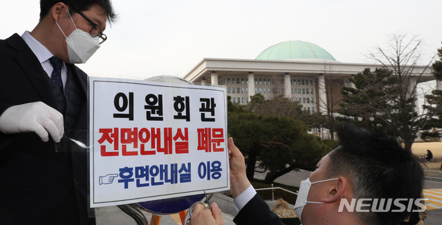 [서울=뉴시스] 김명원 기자 = 신종 코로나바이러스 감염증(코로나19) 확진자가 국회에서 열린 토론회에 참석했던 것이 확인된 24일 오후 서울 여의도 국회 의원회관 앞에서 국회 관계자가 2층 안내실 출입구 폐문을 알리는 안내문을 부착하고 있다. 2020.02.24.&nbsp; photo@newsis.com