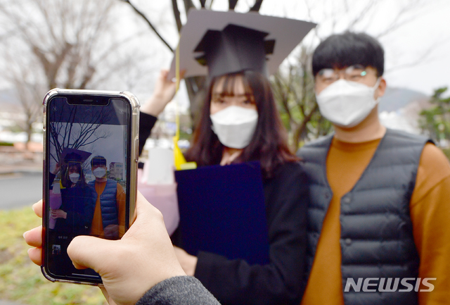 [광주=뉴시스] 류형근 기자 = 신종 코로나 바이러스 감염증(코로나19) 확산d으로 인해 졸업식 등 공식행사 마저 취소된 가운데 26일 오전 광주 동구 조선대학교 단과대학 건물 앞에서 종이학사모를 쓴 졸업생이 기념사진을 찍고 있다. 2020.02.26. hgryu77@newsis.com