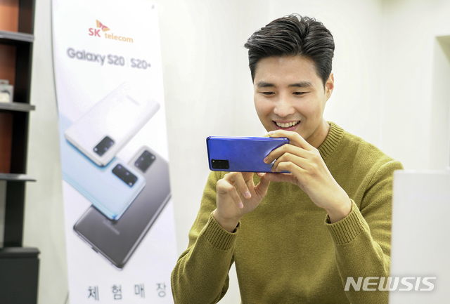 [서울=뉴시스]SK텔레콤 홍보모델이 T월드 매장에서 갤럭시 S20 플러스 '아우라 블루' 모델을 써보고 있다. (사진=SK텔레콤 제공) 2020.02.27