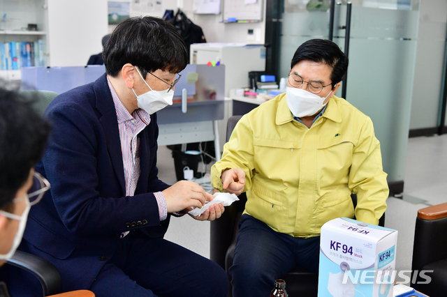 [장성=뉴시스]이창우 기자 = 유두석 전남 장성군수(오른쪽)가 지역 소재 마스크 제조업체인 ㈜화진산업을 방문해 직원들을 격려하고 마스크 품질을 살펴보고 있다. (사진=장성군 제공) 2020.03.01. photo@newsis.com