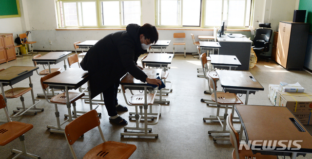 [전주=뉴시스] 김얼 기자= 신종 코로나바이러스 감염증(코로나19)의 여파로 전국의 학교가 휴업한 2일 전북 전주시 전주동초등학교에서 한 교사가 미루어진 개학을 앞두고 살균제로 학생들이 사용할 책상을 닦고 있다. 2020.03.02.pmkeul@newsis.com