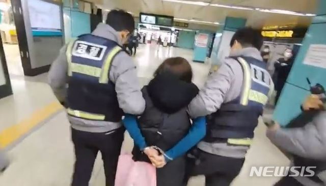 [서울=뉴시스]지난달 서울 잠실역에서 경찰 두명이 한 여성의 등 뒤로 수갑을 채운 채 연행하고 있다. 2020.03.04. (사진=유튜브 캡쳐) photo@newsis.com