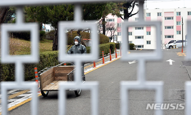 [대구=뉴시스] 이무열 기자 = 신종 코로나바이러스 감염증(코로나19) 확진자가 대거 발생한 7일 대구 달서구 한 아파트 출입구가 코호트 격리로 통제돼 있다. 닫힌 철문 사이로 보건당국 관계자가 자가격리자에게 택배 물건을 전달해주기 위해 분주히 움직이고 있다. 2020.03.07.&nbsp; lmy@newsis.com 