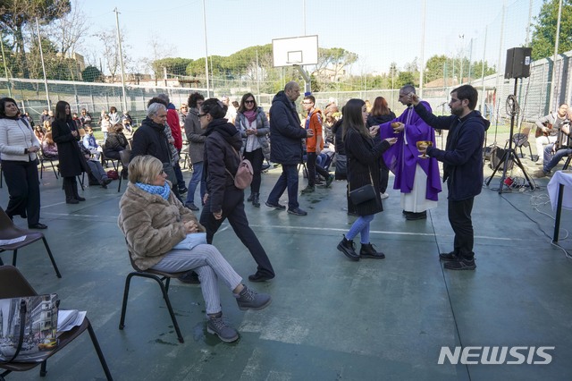 [로마=AP/뉴시스] 8일 이탈리아 로마에서 한 신부가 사순절 두 번째 일요 미사를 코로나19 저지 정부 방침에 따라 축구장 야외에서 집전하면서 신자들에게 영성체를 주고 있다. 이날 북부에 이동금지의 봉쇄령이 내려졌다.  2020. 3. 8.  