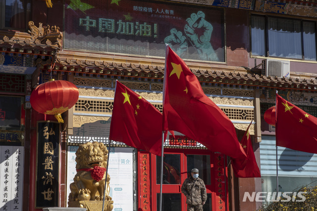 [베이징=AP/뉴시스]3일(현지시간) 중국 베이징에서 한 사람이 중국의 국기인 오성홍기 옆에 서 있다. 2020.03.31. 