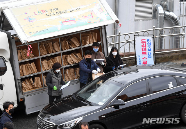 [부산=뉴시스] 하경민 기자 = 신종 코로나바이러스 감염증(코로나19) 확산 여파로 부산지역 공공도서관 임시휴관이 장기화되고 있는 10일 부산 부산진구 시민도서관 주차장에서 직원들이 '북 드라이브 스루'(Book Drive-thru) 서비스를 신청한 시민들에게 도서를 전달하고 있다. 부산에서는 시민도서관과 중앙도서관 등 2곳이 드라이브 스루 안심 도서대출 서비스를 시행하며, 이날 시민도서관에는 총 250명이 이 서비스 이용을 신청했다. 2020.03.10. yulnetphoto@newsis.com