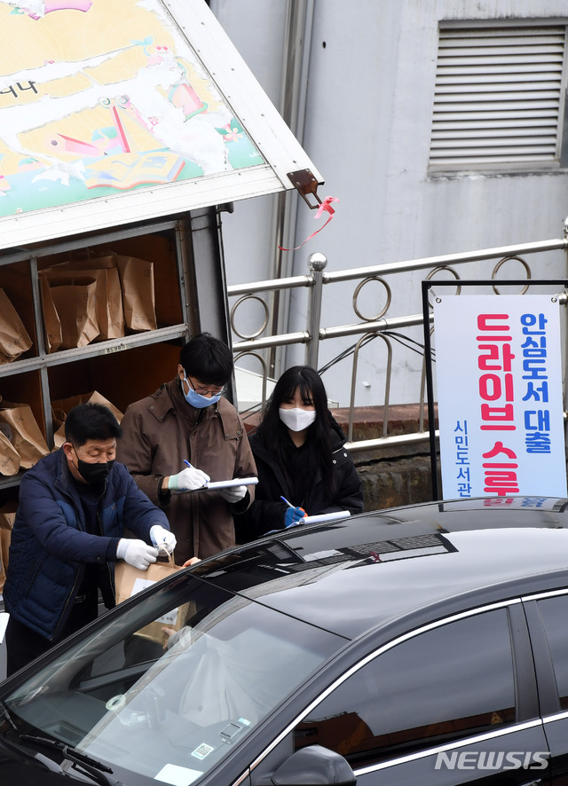 [부산=뉴시스] 하경민 기자 = 신종 코로나바이러스 감염증(코로나19) 확산 여파로 부산지역 공공도서관 임시휴관이 장기화되고 있는 10일 부산 부산진구 시민도서관 주차장에서 직원들이 '북 드라이브 스루'(Book Drive-thru) 서비스를 신청한 시민들에게 도서를 전달하고 있다. 부산에서는 시민도서관과 중앙도서관 등 2곳이 드라이브 스루 안심 도서대출 서비스를 시행하며, 이날 시민도서관에는 총 250명이 이 서비스 이용을 신청했다. 2020.03.10. yulnetphoto@newsis.com