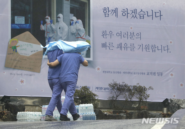 [대구=뉴시스] 최동준 기자 = 의료진들이 10일 대구 중구 계명대학교 동산의료원에서 의료복을 함께 쓰고 비를 피해 이동하고 있다. 2020.03.10. photocdj@newsis.com