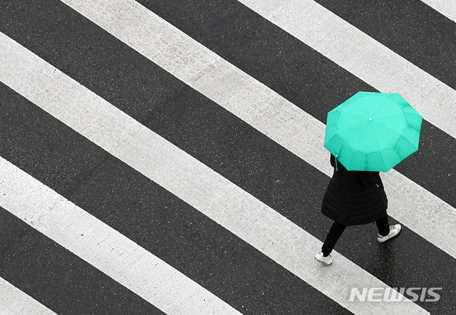 [서울=뉴시스] 이영환 기자 = 한 시민이 봄비가 내린 10일 오후 서울 중구 세종대로의 건널목을 건너고 있다. 2020.03.10.&nbsp;&nbsp; 20hwan@newsis.com