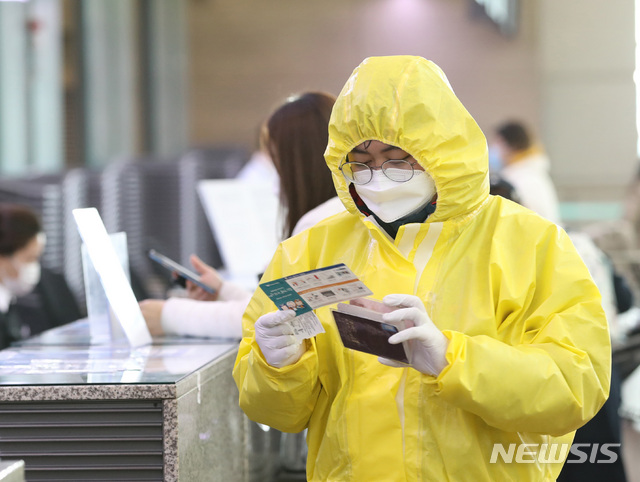 [인천공항=뉴시스] 전진환 기자 = 13일 오전 인천공항 발권창구에서 한 출국 승객이 보호복을 입고 항공편 티켓을 확인하고 있다. 2020.03.13. amin2@newsis.com