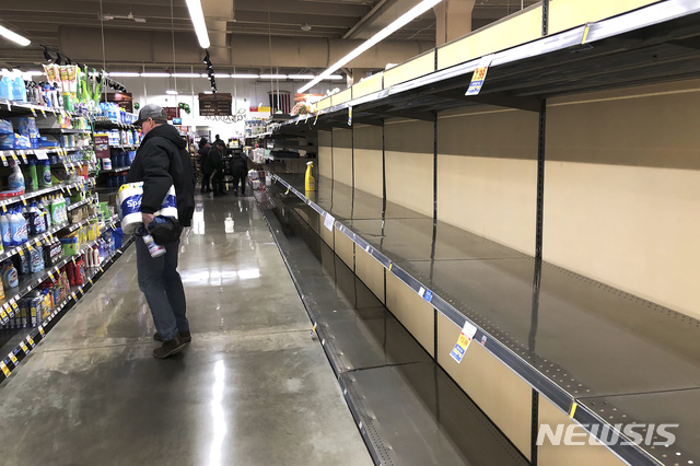 [시카고(미 일리노이주)=AP/뉴시스]미 일리노이주 시카고의 한 슈퍼마켓에서 지난 14일 화장지를 들고 있는 쇼핑객 1명이 텅 빈 식품 진열대 건너편의 청소용품들을 살펴보고 있다.&nbsp; 2020.3.15