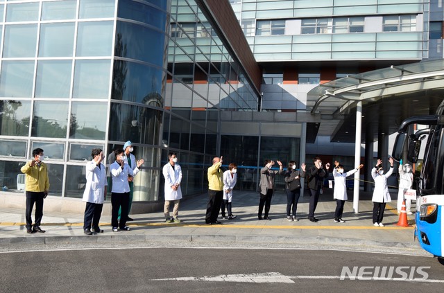 [창원=뉴시스] 근로복지공단 창원병원 의료진이 16일 오후 완치 판정을 받고 퇴원한 대구·경북지역 '코로나19' 확진자 26명이 탄 버스를 배웅하고 있다.(사진=창원병원 제공) 2020.03.16. photo@newsis.com