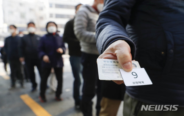 [서울=뉴시스] 박민석 기자 = 마스크 5부제 정책 시행 둘째 주인 지난 18일 오전 서울 종로구 인근 한 약국에서 시민들이 공적마스크를 구매하기 위해 번호표를 받아 줄을 서 있다. 2020.03.18. mspark@newsis.com