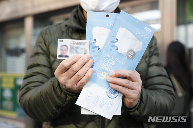 [서울=뉴시스] 박민석 기자 = 마스크 5부제 정책 시행 둘째 주인 18일 오전 서울 종로구 인근 한 약국에서 한 시민이 공적마스크와 신분증을 들고 있다. 2020.03.18. mspark@newsis.com