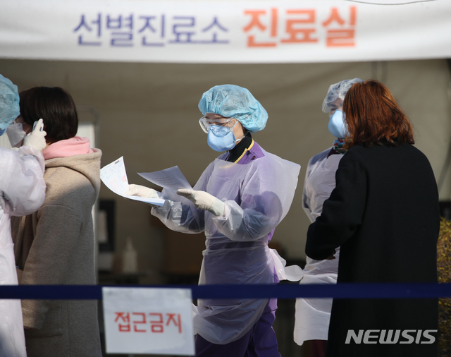 [서울=뉴시스] 조수정 기자 = 18일 오전 서울 중랑구 신내동 서울의료원에서 의료진이 이른 아침부터 신종 코로나 바이러스 감염증(코로나19) 검사를 받기 위해 선별진료소를 찾은 의심환자의 발열 여부와 문진표 등을 확인하고 있다. 2020.03.18. chocrystal@newsis.com