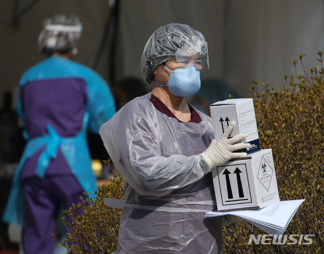 [서울=뉴시스] 조수정 기자 = 18일 오전 서울 중랑구 신내동 서울의료원 신종 코로나 바이러스 감염증(코로나19) 선별진료소에서 의료진이 '감염성 물질', 'UN3373'이라고 적힌 상자를 옮기고 있다. 방호를 위해 머리에 쓴 비닐 속으로 습기와 땀이 흥건하다. 2020.03.18. chocrystal@newsis.com