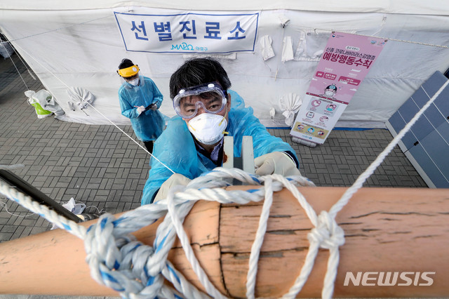 [서울=뉴시스]김병문 기자 = 선별진료소 의료진이 18일 오후 서울 마포구 보건소 선별진료소에서 내일 예보된 강풍에 대비해 끈으로 고정하고 있다. 2020.03.18. dadazon@newsis.com