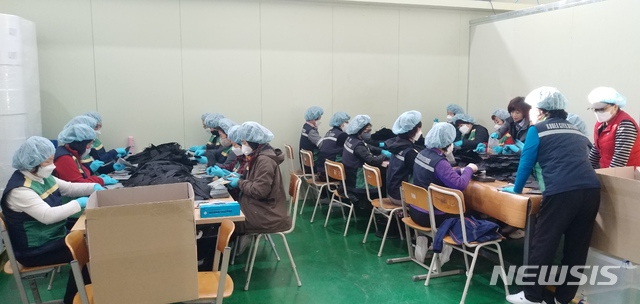 [밀양=뉴시스] 경남 밀양시 주부 민방위기동대가 상남면 마스크 생산업체인 그린동화에서 마스크 생산 일손 돕기를 하고 있다.(사진=밀양시 제공) 2020.03.20. photo@newsis.com