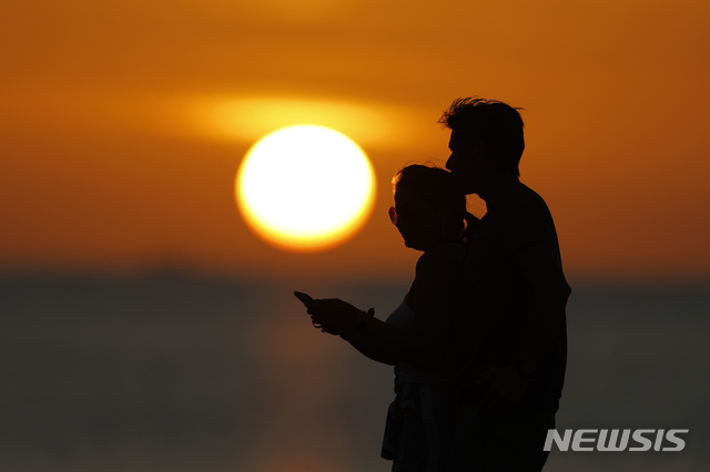 [이스트포인트=AP/뉴시스]19일(현지시간) 미 플로리다주 이스트포인트의 세인트 조지 섬에서 일몰을 감상하던 한 남성이 약혼녀 머리에 입 맞추고 있다. 2020.03.20.