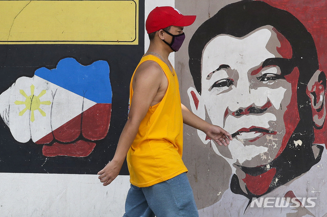 [마닐라=AP/뉴시스] 신종 코로나바이러스 감염증(코로나19)이 확산하는 가운데 필리핀 마닐라에서 마스크를 낀 한 남성이 로드리고 두테르테 대통령 벽화 앞을 지나고 있다. 2020.03.30.