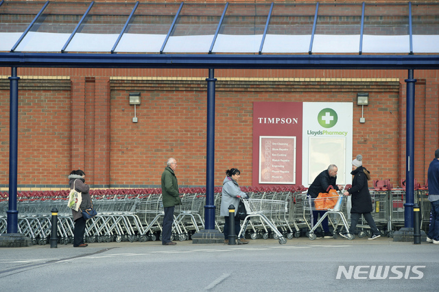 [콜턴=AP/뉴시스] 지난달 24일 영국 콜턴 지역의 슈퍼마켓 체인점 세인즈버리 앞에서 영국인들이 쇼핑 카트를 끌며 줄을 서있다. 그동안 1인당 상품 구매 개수를 제한해오던 세인즈버리는 3일(현지시간) "오는 5일부터 구매 개수 제한 조치를 해제한다"고 밝혔다. 2020.4.3.