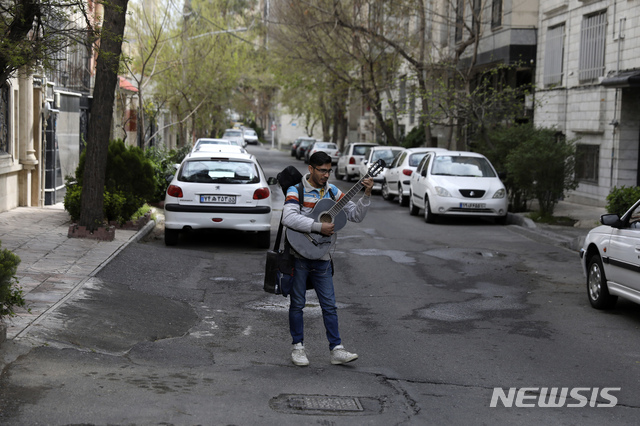 [테헤란=AP/뉴시스] 26일 이란 수도의 빈 주택가 도로에서 한 뮤지션이 음악을 연주하고 노래하고 있다 2020. 3. 26. 