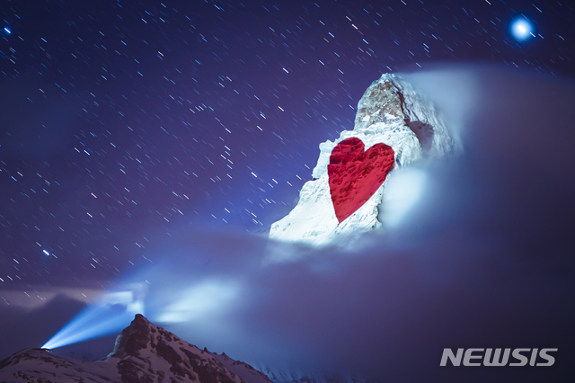 [체르마트(스위스)=AP/뉴시스]26일(현지시간) 스위스 체르마트의 알파인 휴양지에서 조명 아티스트 '게리 호프슈테터'(Gerry Hofstetter)가 마터호른산에 신종 코로나바이러스 감염증으로 고통받는 사람들을 위해 희망과 응원의 메시지를 비추고 있다. 2020.03.27.