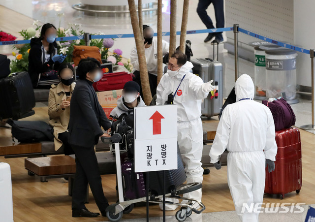 [인천공항=뉴시스] 고범준 기자 = 신종 코로나바이러스 감염증(코로나19) 무증상자의 안전 귀가를 위해 해외입국자 전용 KTX칸과 공항버스가 운행되고 있는 가운데 29일 오후 인천국제공항 제2터미널에서 독일 프랑크푸르트와 영국 런던 발 여객기를 타고 입국한 승객들이 방역관계자들에게 KTX와 지방 이동 등에 대한 안내를 받고 있다. 2020.03.29. bjko@newsis.com