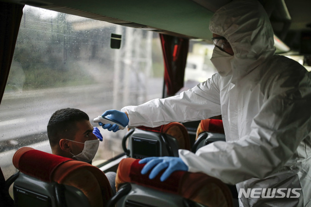 [이스탄불=AP/뉴시스]29일(현지시간) 터키 이스탄불의 검문소에서 보건당국 관계자가 신종 코로나바이러스 감염증(코로나19) 방역을 위해 버스 승객의 체온을 확인하고 있다. 2020.3.30.