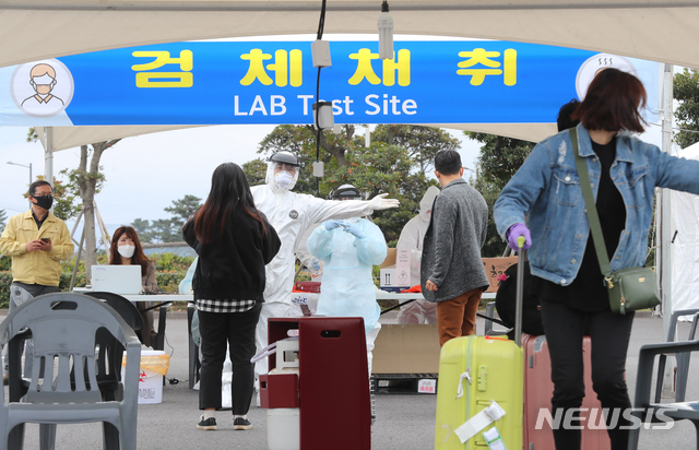 [제주=뉴시스]우장호 기자 = 신종 코로나바이러스 감염증(코로나19)이 확산 중인 30일 제주국제공항 내에 마련된 워킹 스루 진료소(개방형 선별진료소)에서 국외 입국자를 대상으로 코로나19 검사가 진행되고 있다. 2020.03.30.&nbsp; woo1223@newsis.com