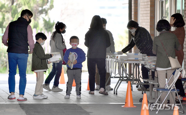 [광주=뉴시스] 류형근 기자 = 신종 코로나 바이러스 감염증(코로나19)이 지속되고 있는 가운데 30일 오전 광주 서구 광천초등학교에서 어린이들이 교재를 받고 있다. 2020.03.30. hgryu77@newsis.com