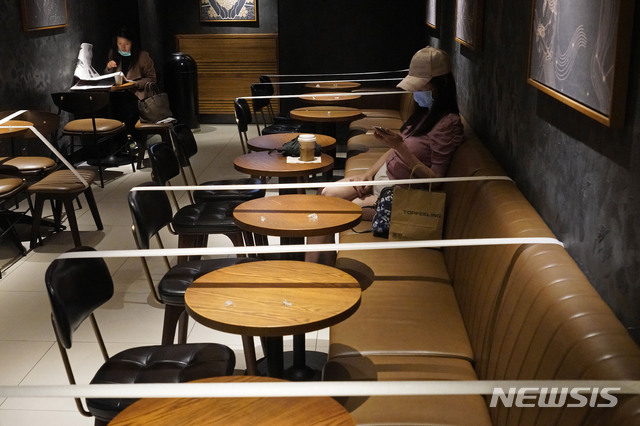 [홍콩=AP/뉴시스]30일(현지시간) 홍콩의 한 스타벅스 매장에 신종 코로나바이러스 감염증 확산 예방을 위한 홍콩 정부의 사회적 거리 두기 지침에 따라 일정 테이블과 의자에 테이프가 둘려 있다. 2020.03.30.