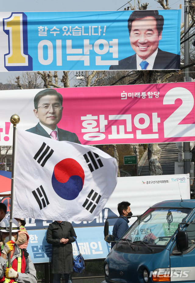 [서울=뉴시스] 고승민 기자 = 태극기를 든 한 남성이 2일 서울 종로구 평창동주민센터 주변 일대에 걸린 이낙연 더불어민주당 종로구 후보와 황교안 미래통합당 후보의 현수막 아래 서 있다. 2020.04.02.kkssmm99@newsis.com