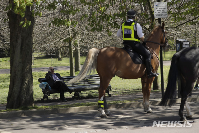  [런던=AP/뉴시스] 5일 영국 수도 그린위치 공원에서 기마경찰이 코로나 19 자택칩거령에 위반된다며 공원 벤치에 홀로 신문 보던 사람에게 일어나 집에 가라고 요구하고 있다. 2020. 4. 5.&nbsp;&nbsp; 
