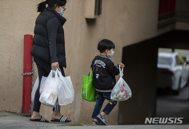 [로스앤젤레스=AP/뉴시스] 2일 미국 로스앤젤레스의 차이나타운에서 마스크를 착용한 여성과 어린이가 양손 가득 짐을 들고 이동 중이다. 미국에서도 신종 코로나바이러스 감염증(코로나19)과 연관된 것으로 의심되는 어린이 괴질 중환자가 나왔다고 CNN은 28일(현지시간) 보도했다. 스페인과 영국, 이탈리아 등에서는 이미 관련 질병으로 인한 어린이 사망 사례가 보고됐다. 2020.4.29.