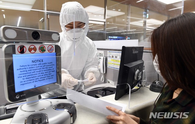 [인천공항=뉴시스] 고범준 기자 = 신종 코로나바이러스 감염증(코로나19) 사태가 장기화되고 있는 가운데 8일 전신 방호복을 입은 인천국제공항 출입국 외국인청 입국심사관이 유증상자 전용 입국심사대에서 입국심사뒤 자가격리 지침을 설명하고 있다. 2020.04.08. photo@newsis.com