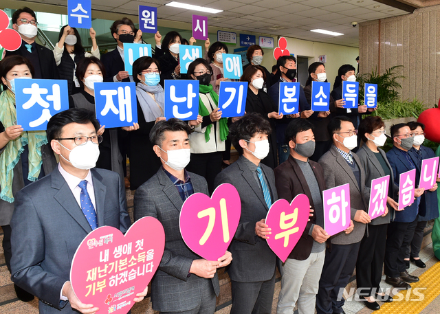 【수원=뉴시스】김경호 기자= 경기 수원시·경기사회복지공동모금회 관계자, 나눔 캠페인 참여자들이 9일 수원시청 본관 1층에서 '내 생애 첫 재난 기본 소득을 기부하겠습니다'라는 글이 적힌 카드를 들고 있다.