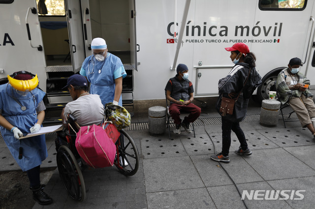 [멕시코시티=AP/뉴시스]멕시코 의료진이 8일 멕시코시티의 과달루페 성모 마리아 바실리카 밖에 설치된 이동 보건소에서 휠체어를 탄 환자를 돌보고 있다. 멕시코 국가인권위원회는 8일(현지시간) 신종 코로나바이러스 감염증(코로나19) 확산으로 대규모 집회와 비필수 서비스에 대한 단속이 실시되는 가운데 여성 댄서 등 접대부들을 집으로 보내준다는 광고를 한 나이트클럽에 대한 조사를 당국에 요청했다. 2020.4.9