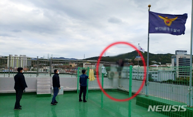[부산=뉴시스] 부산 금정경찰서 4층 옥상 난간에서 투신소동을 벌이고 있는 60대. (사진=부산경찰청 제공)