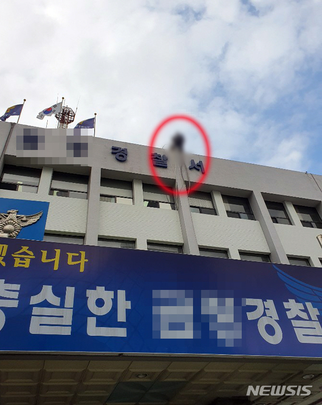 [부산=뉴시스] 부산 금정경찰서 4층 옥상 난간에서 투신소동을 벌이고 있는 60대. (사진=부산경찰청 제공) 