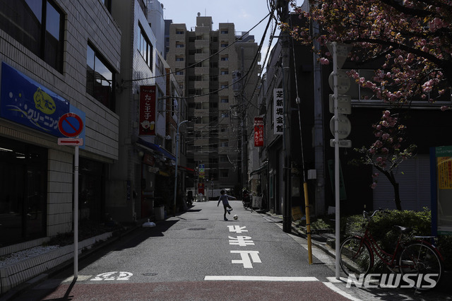 [도쿄=AP/뉴시스]일본에 긴급사태 선언 후 첫 주말을 맞은 11일 도쿄의 텅빈 한 거리에서 한 어린이가 공을 차며 놀고 있다. 신종 코로나바이러스 감염증(코로나19) 환자의 급증으로 일본의 의료 시설들이 추가로 환자들을 받을 수 있는 여력을 점점 잃어가고 있다. 2020.04.12