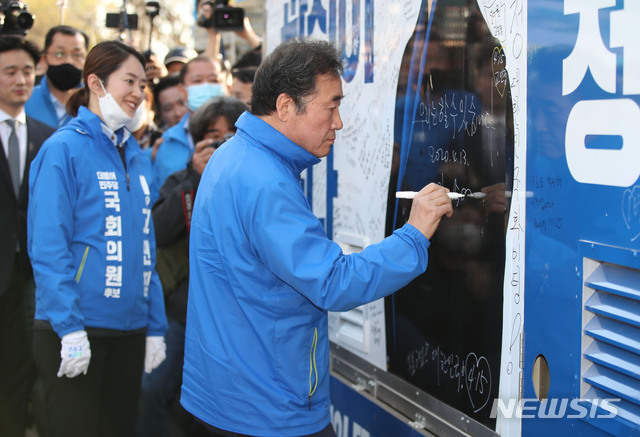 [서울=뉴시스] 김진아 기자 = 이낙연 더불어민주당 공동상임선대위원장이 13일 서울 광진구 건대입구역 사거리 인근에서 서울 광진갑 전혜숙 후보, 광진을 고민정 후보 지원유세를 후 고민정 후보 유세차에 ‘우리는 할 수 있습니다’를 적고 있다. 2020.04.13.&nbsp; bluesoda@newsis.com