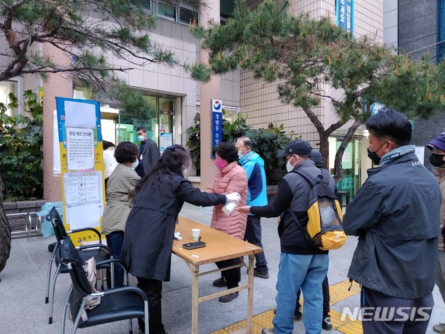 [통영=뉴시스]신정철 기자= 21대 총선 경남 통영시·고성군 국회의원 선거구 투표가 15일 오전 6시부터 총 73개 투표소에서 순조롭게 개시됐다. 이날 통영시 정량동주민센터에 마련된 정량1투표소 입구에는 오전 6시께 유권자들이 마스크를 착용하고 1m 거리두기를 하면서 손소독과 발열검사를 받고 있다. 2020.04.15.    sin@newsis.com 