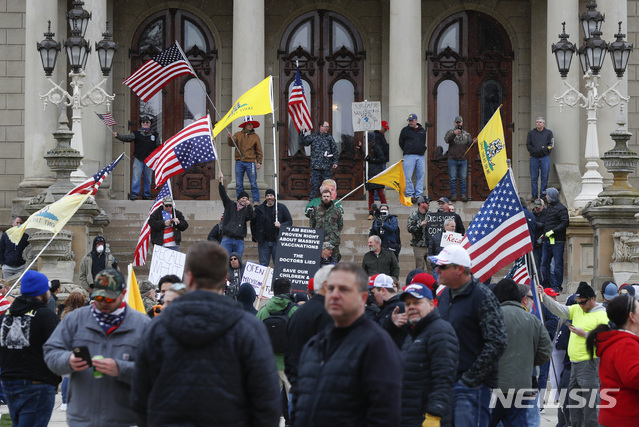 [랜싱=AP/뉴시스]15일(현지시간) 미 미시간주 랜싱의 미시간 의사당 계단에 시민들이 그레첸 위트머 미시간주지사가 신종 코로나바이러스 감염증(코로나19) 확산 예방을 위해 내린 자택 체류 명령에 반대하는 시위를 벌이며 모여 있다. 수백 명의 시위대는 깃발을 흔들고 경적을 울리며 의사당 앞에 모여 코로나19 예방을 위해 집에 머물라는 위트머 주지사의 명령에 불쾌감을 나타냈다. 2020.04.16.