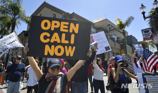 [헌팅턴비치=AP/뉴시스]17일(현지시간) 미국 캘리포니아 헌팅턴비치에서 시위대가 '당장 캘리포니아를 개방하라'는 팻말을 들고 시위를 벌이고 있다. 2020.04.18.
