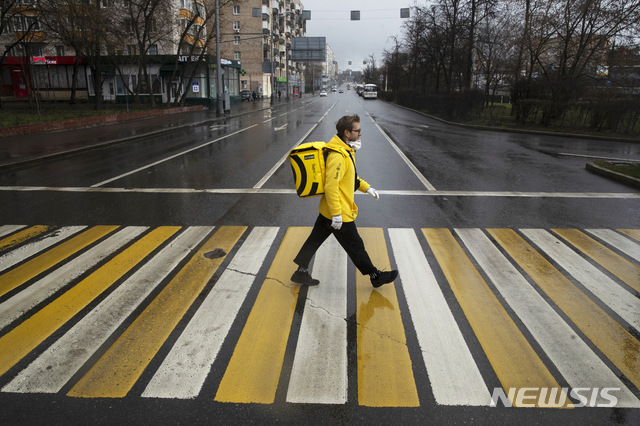 [모스크바=AP/뉴시스]컨설팅 사업을 하던 38살의 모스크바 사업가 세르게이 노초브니가 16일 신종 코로나바이러스 감염증(코로나19)로부터 보호하기 위해 마스크를 쓰고 음식 배달을 위해 텅 빈 모스크바 도로를 건너고 있다. 연간 200만 달러(24억3400만원)의 수입을 올리던 그는 현재 음식 배달로 하루 1000~1500루블(약 1만6500~2만5000원)을 받지만 배달원 생활이 봉쇄 조치로 불가능했던 육체적 활동을 할 수 있게 해줄 뿐만 아니라 끝없이 인터넷을 배회하는 일로부터 벗어나게 해준다고 말했다. 2020.4.20