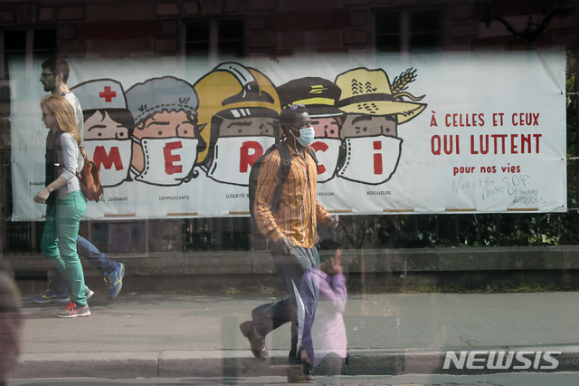 [파리=AP/뉴시스]지난달 20일(현지시간) 프랑스 파리에서 행인들이 신종 코로나바이러스 감염증(코로나19)과 싸우는 의료진 및 경찰관 등에 고마움을 표하는 현수막 앞을 지나고 있다. 2020.05.09