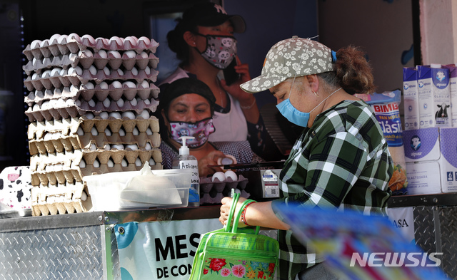 [멕시코시티=AP/뉴시스]20일(현지시간) 멕시코 수도 멕시코시티의 산 그레고리오 아틀라풀코 시장에서 신종 코로나바이러스 감염증(코로나19) 예방을 위해 마스크를 쓴 한 여성이 달걀을 사고 있다.. 2020.04.21.