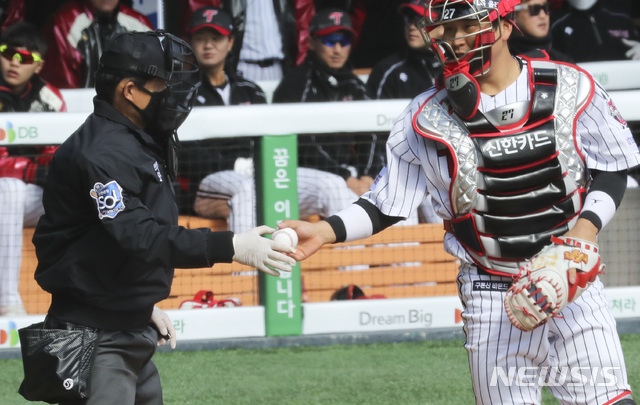 [서울=뉴시스]최진석 기자 = KBO가 정규시즌 개막을 5월 5일로 확정한 21일 서울 송파구 잠실야구장에서 열린 두산 베어스와 LG 트윈스의 연습경기에서 오훈규 심판이 신종 코로나바이러스 감염증(코로나19) 예방을 위해 마스크와 위생장감을 낀 채 LG 포수 유강남에게 공을 건네고 있다. 2020.04.21. myjs@newsis.com