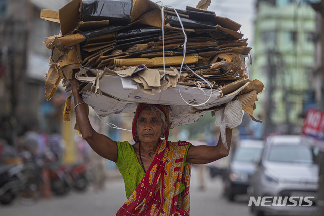 [가우하티=AP/뉴시스]인도 전역이 신종 코로나바이러스 감염증(코로나19) 확산 예방을 위해 봉쇄된 가운데 23일(현지시간) 인도 가우하티에서 한 나이든 여성이 재활용 상자를 머리에 이고 옮기고 있다. 인도는 코로나19 확산 예방을 위해 하루 1.90달러의 임금으로 근근이 살아가는 약 1억7600만 명을 포함, 인구 전체를 봉쇄하면서 역사상 가장 엄격한 제재 조치를 취하고 있다. 2020.04.24.